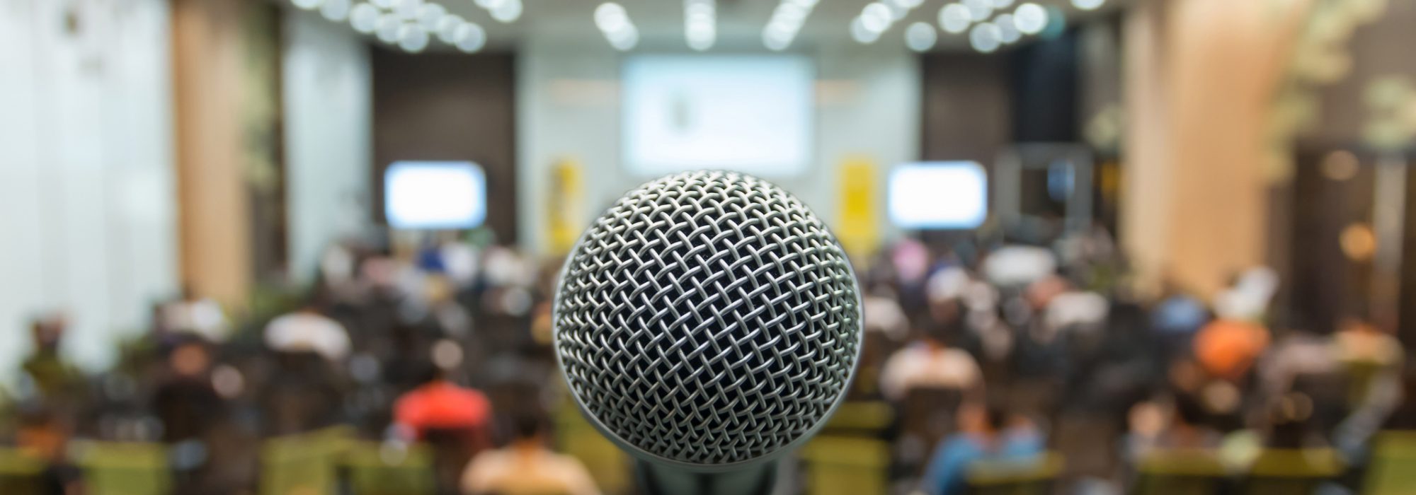 Microphone over the Abstract blurred photo of conference hall or seminar room with attendee background