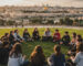 קבוצת נוער ישראלי יושב במעגל על דשא ירוק בשקיעה, מנהל שיח עמוק מול נוף ירושלים העתיקה עם כיפת הסלע וחומות העיר, סדנה חווייתית על ציונות, אהבת הארץ, זהות ושייכות.